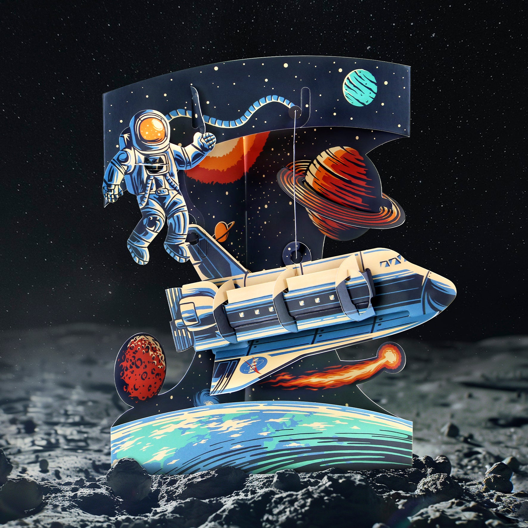 An illustration from the Santoro Swing Card: Space Shuttle features an astronaut floating near a spaceship among colorful planets and stars, with the moon’s rocky surface and outer space as the backdrop.