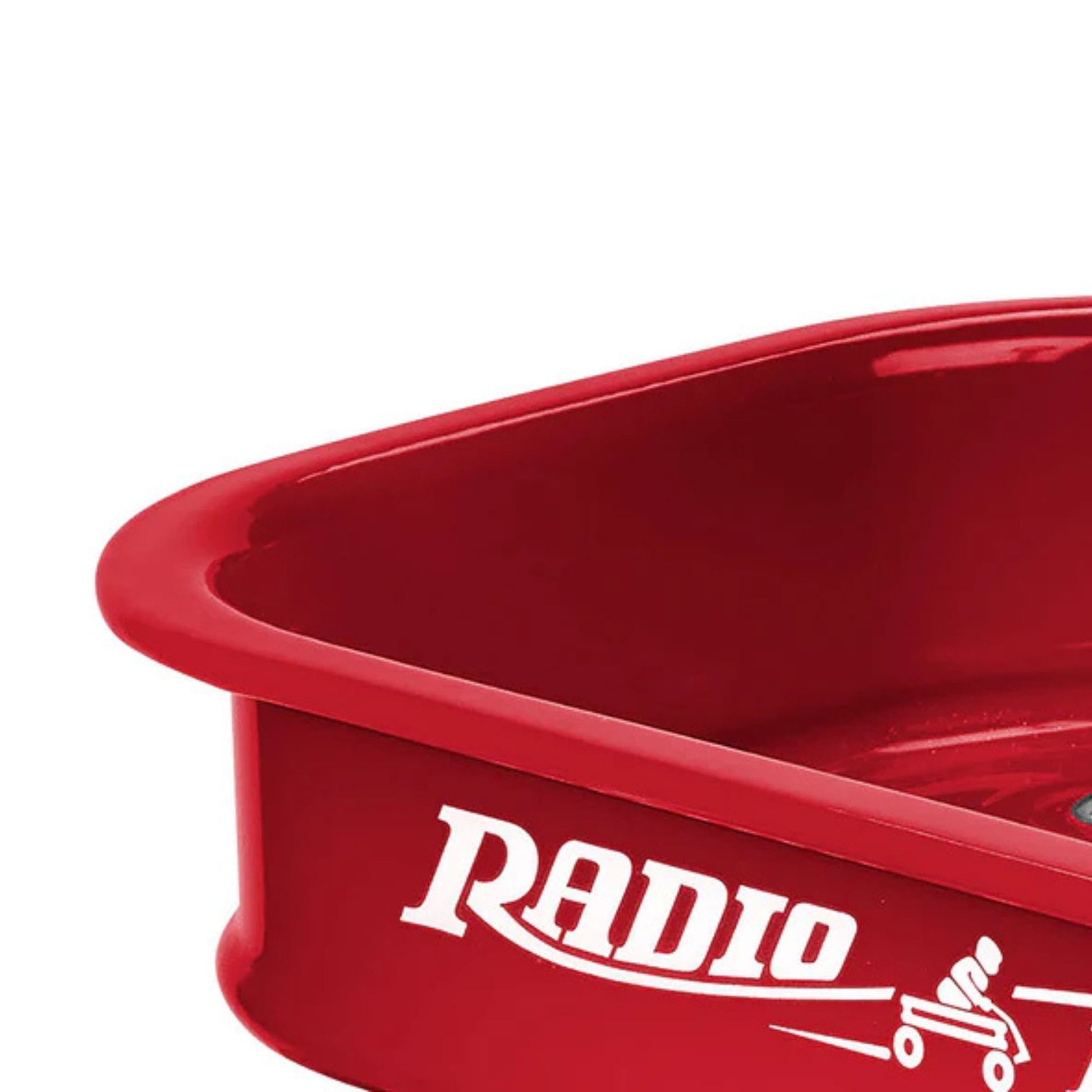 Close-up of the Radio Flyer Little Red Toy Wagon, a red metal miniature wagon by Radio Flyer with "RADIO" and a small wagon graphic in white on the side, shown partially against a white background.