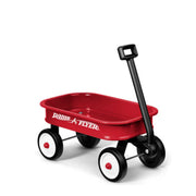 The Radio Flyer Little Red Toy Wagon by Radio Flyer features four black-and-white wheels and a long black handle, making it perfect for imaginative play. The wagon is displayed on a white background.