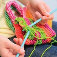 Someone crochets with the 4M-Craft Easy To Do Crochet set by 4M-Craft, using vibrant yarns to create a colorful, textured fabric.