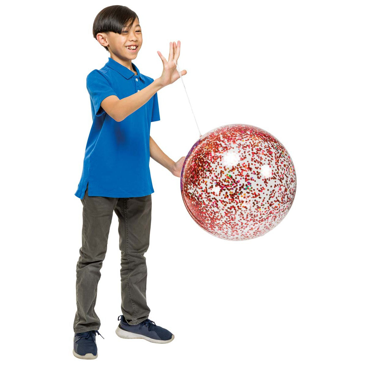A smiling child in a blue shirt and gray pants plays with a Toysmith Jumbo Punch Balloon from Toysmith, filled with red and white confetti and attached to a string. The background is white.