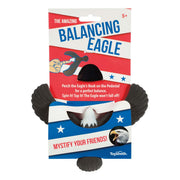Packaging for the Toysmith Balancing Eagle magic toy features a black eagle balanced by its beak on a pedestal. The red, white, and blue design with stars and bold text highlights that it’s suitable for ages 5 and up. Brand: Toysmith.