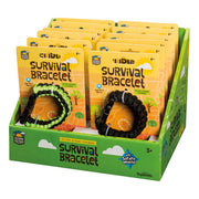 A display box holds several Outdoor Discovery Survival Bracelets by Outdoor Discovery in yellow packaging. Two paracord bracelets—one black and one black with green—are visible, with packaging highlighting a safety whistle and outdoor use.