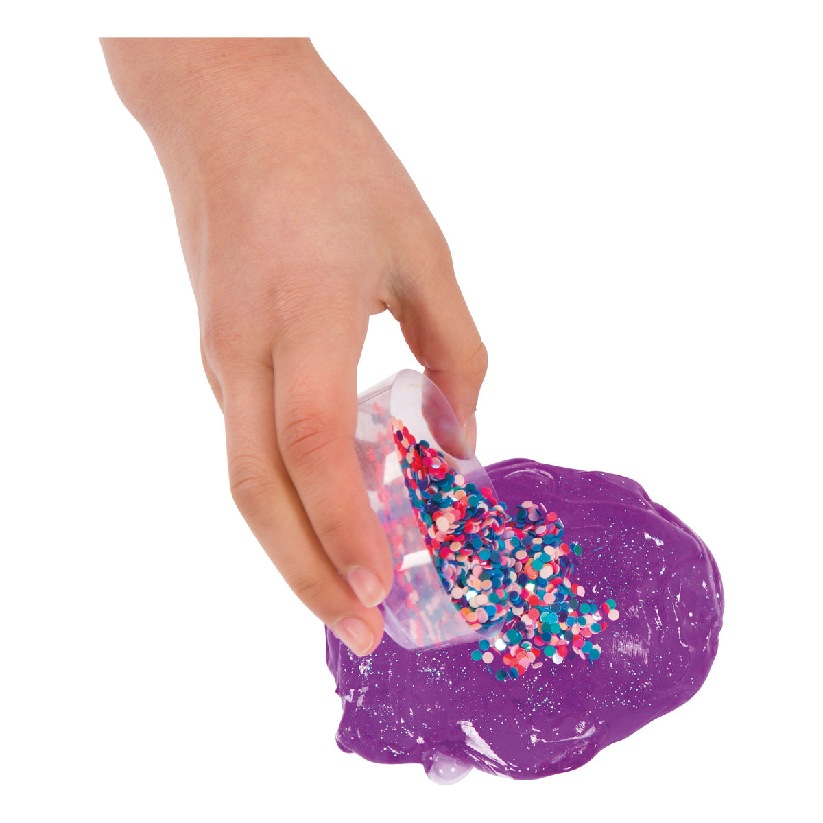 A hand pours Toysmith Mix-Ins Slime Asst by Toysmith from a small clear container onto a shiny purple slime puddle, set against a white background.