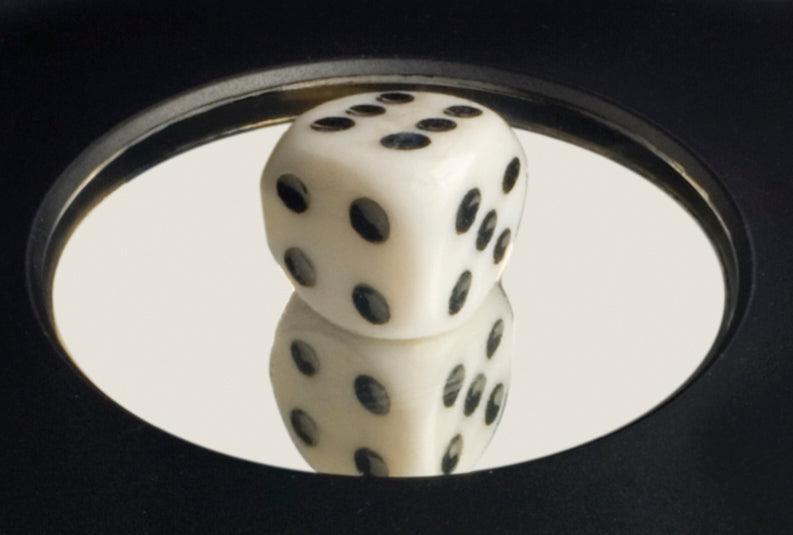 A white die with black dots rests on the Toy Science 3-D Mirascope by Toy Science, creating an optical illusion that makes its reflection appear surprisingly real on the mirrored display.
