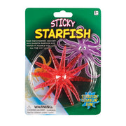 The Toysmith Sticky Starfish by Toysmith features a red, non-toxic plastic starfish inside illustrated packaging. It highlights wall-tumbling action and warns about small parts not suitable for children under 3.